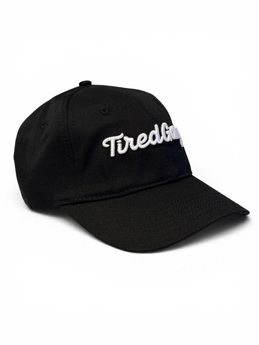 Black dad hat with white embroidered “tired gang” logo on a white background