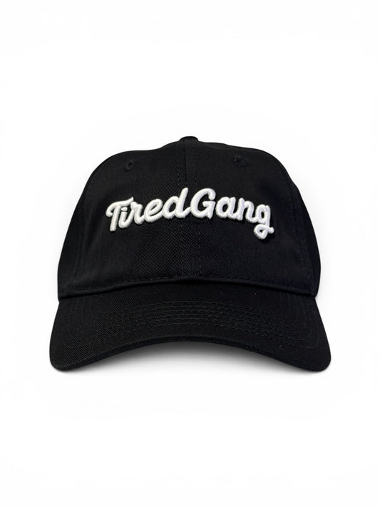 Black dad cap with white embroidered 'Tired Gang' text on a white background